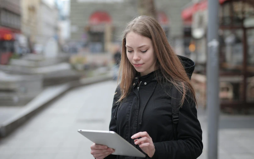 woman using an electronic device on a city sidewalk