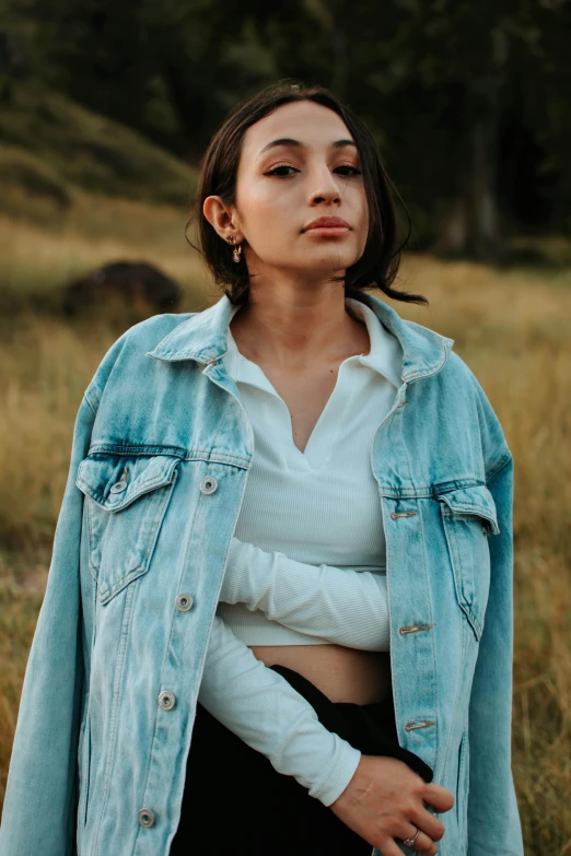 the woman is sitting down in a field wearing jeans