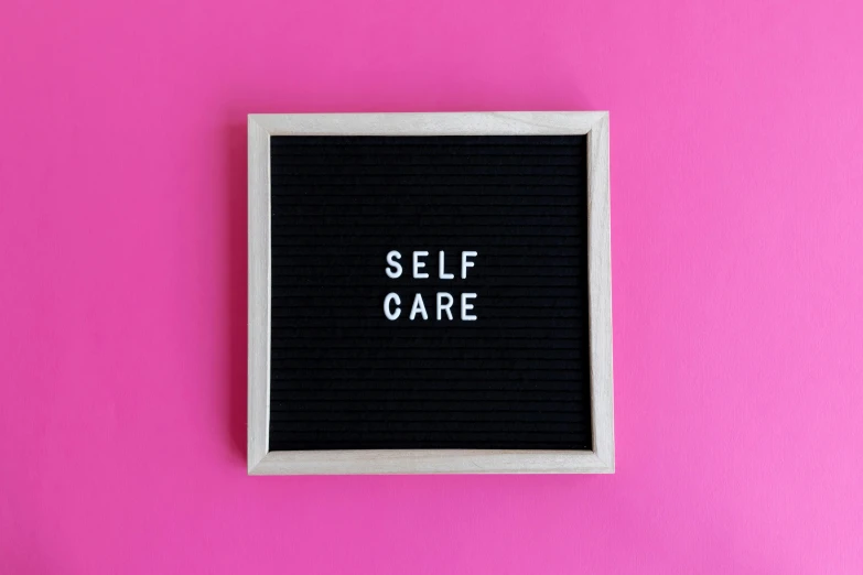 black piece of cloth has a white square frame that reads self care on it