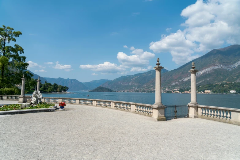 a white fence surrounding a stone walkway and body of water