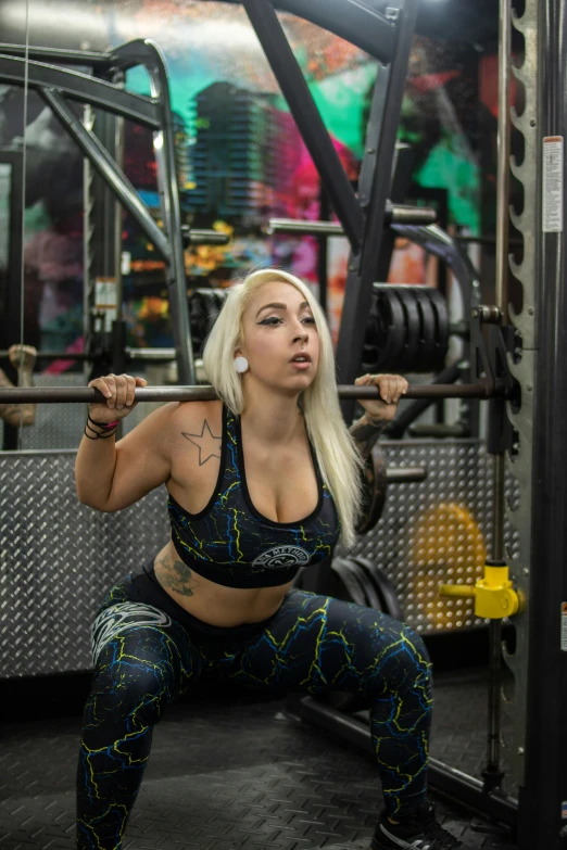 a beautiful young lady squatting while holding a barbell