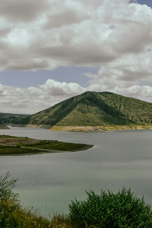 a large body of water surrounded by a green mountain