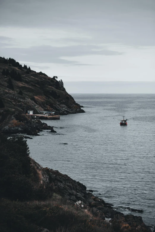 a boat is floating in the water beside a rocky shore