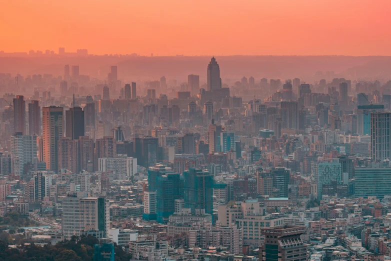 an orange sunset and pink sky above a city