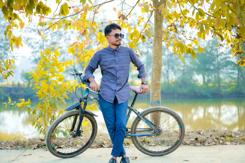 a man stands next to his bicycle by the river
