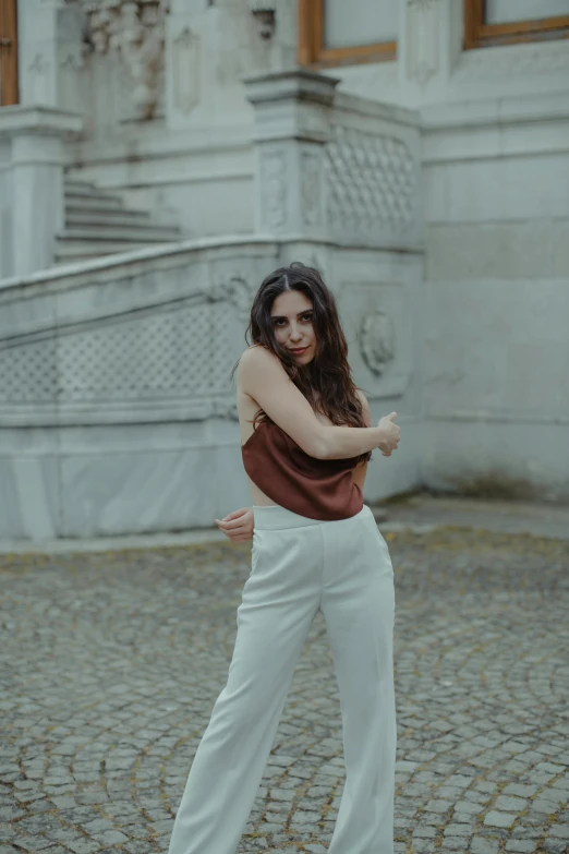 a girl poses in front of a stone building