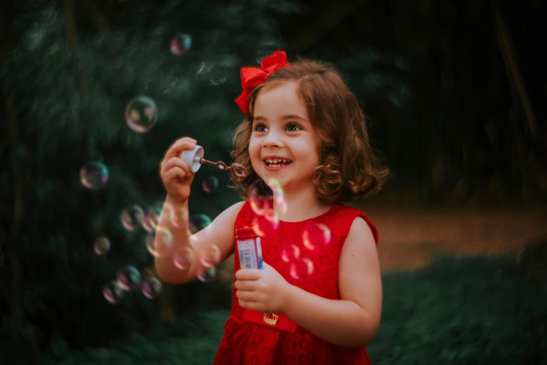 a girl in a red dress holds onto a soap bar and bubbles