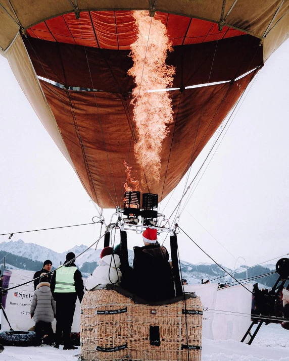 a group of people standing in the snow next to an air balloon