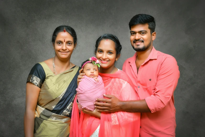 family posing for an infant po wearing a pink sari