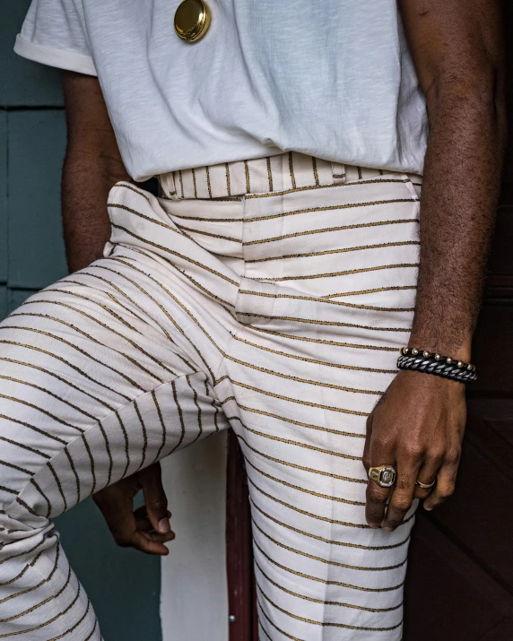 a man in striped pants and gold rings sits