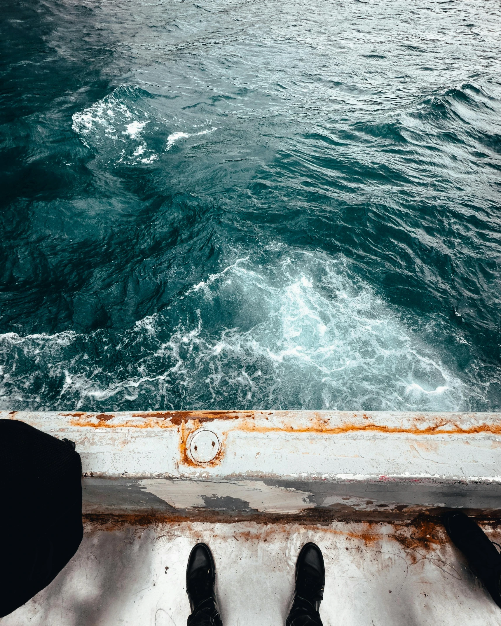 two people stand on a dock in front of an ocean