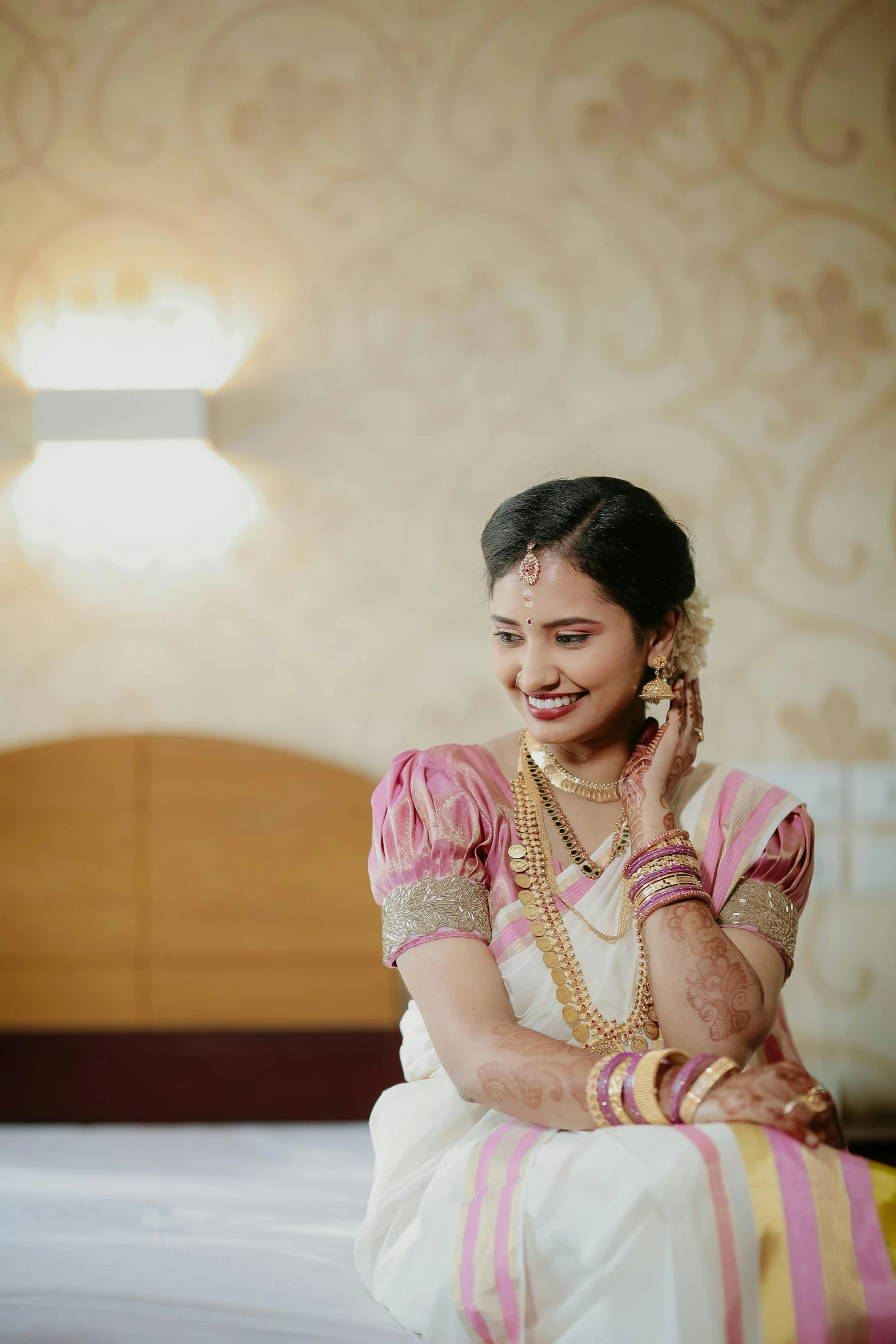 a woman in a pink and white bridal outfit smiles while on her cell phone