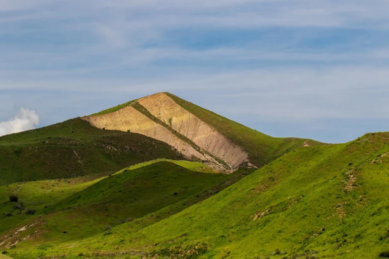 the mountain side has green hills and blue sky