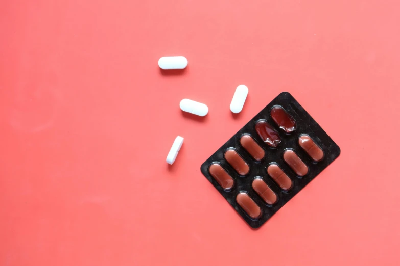 a contration laying on a pink table next to pill cases