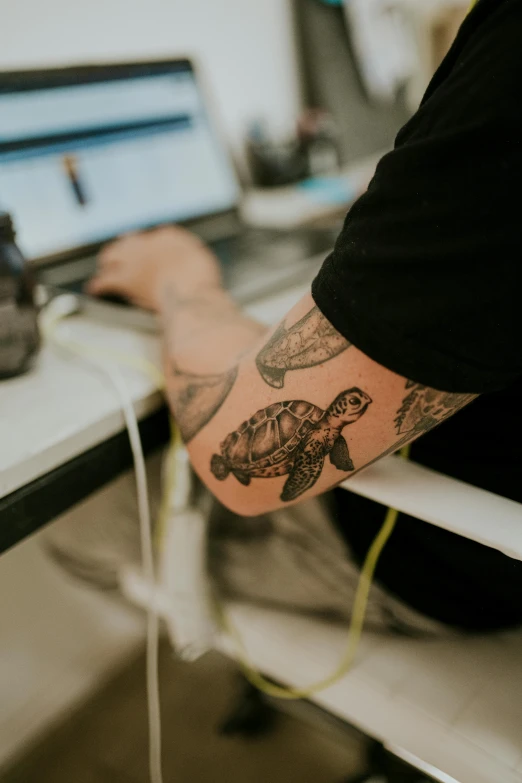 a hand sitting on a table with a laptop