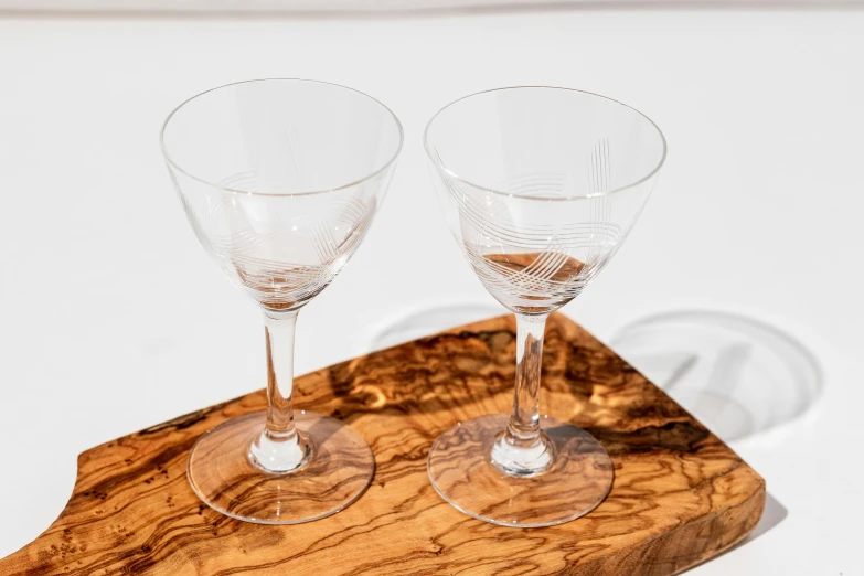 two wine glasses sit on a wooden stand