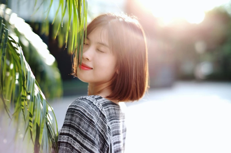 a beautiful asian woman looking up next to a tree