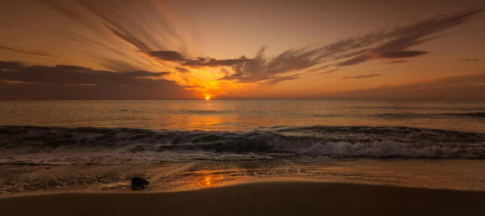 the sun set on the ocean with clouds in the sky