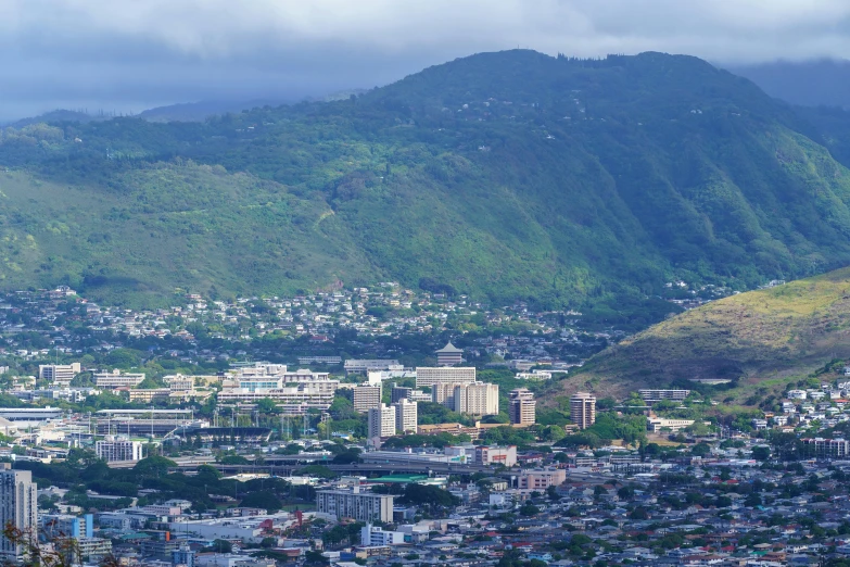 a city surrounded by mountains with a green hills in the background