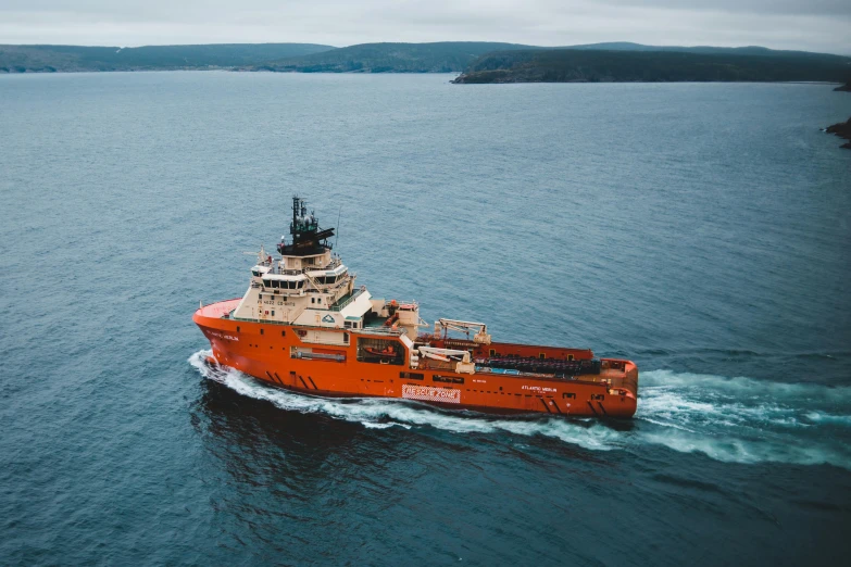 an orange boat is in the ocean with its sails facing upwards