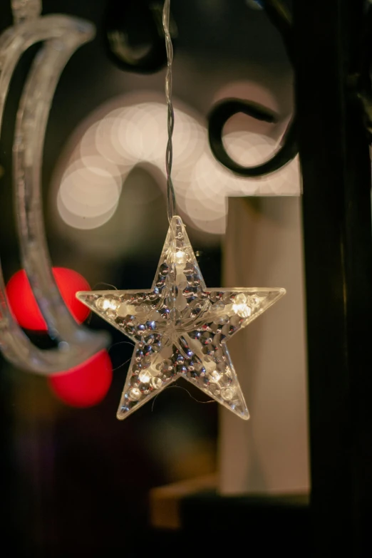 a lighted star hangs from a curtain pole