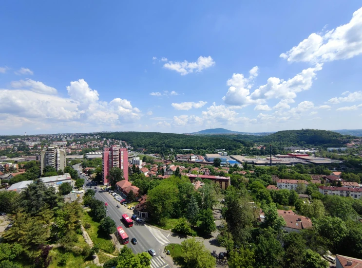 the city is surrounded by green trees and mountains