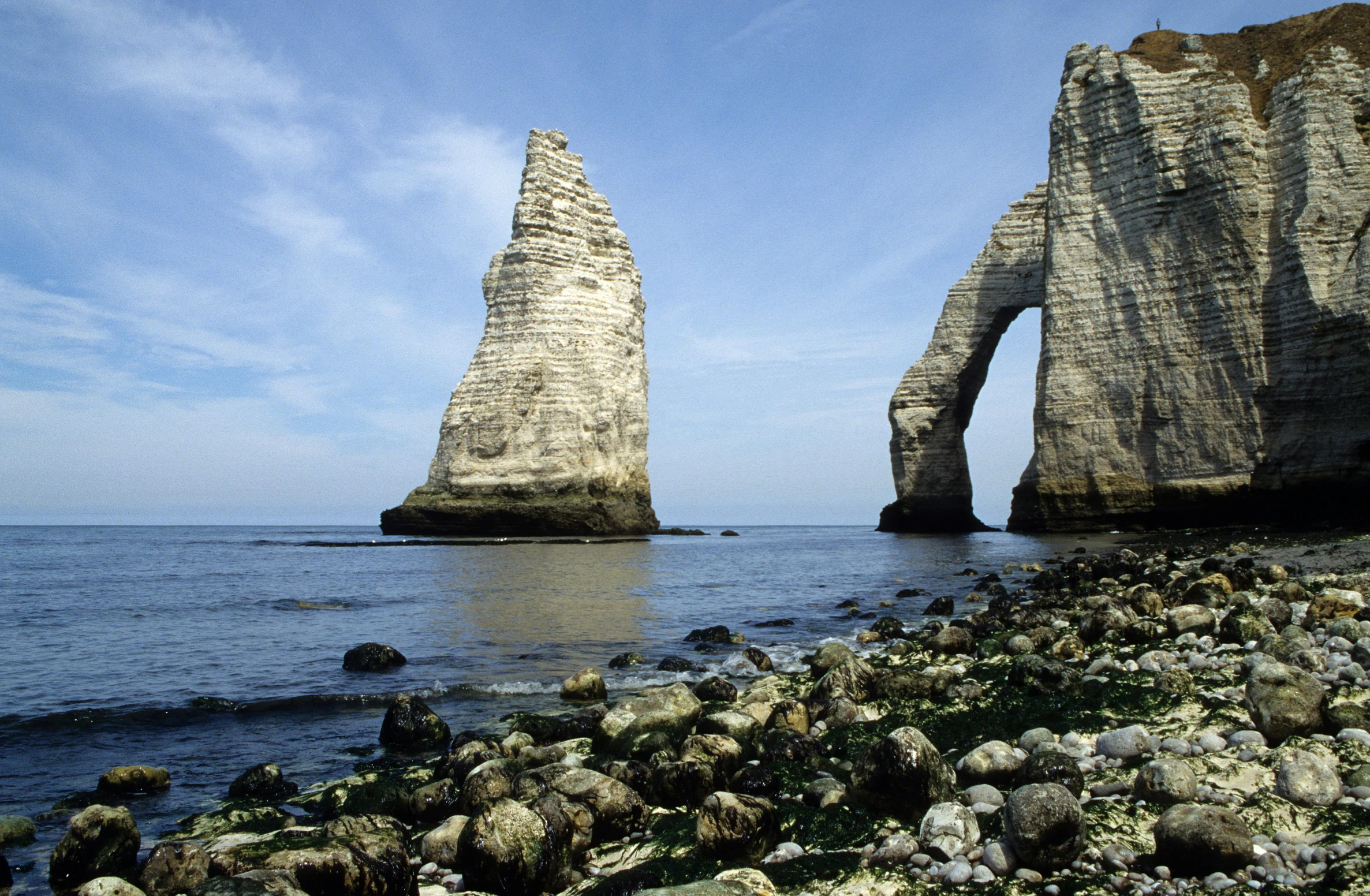 three tall rocks sticking out of the water with rocky shoreline