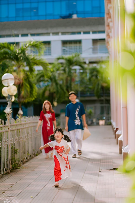 an asian child running with an adult in the background