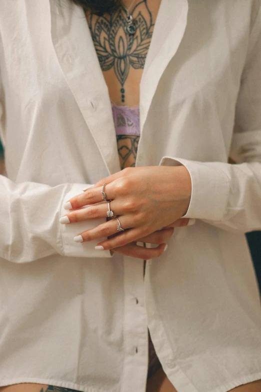 a woman in white shirt holding her hands with tattoos