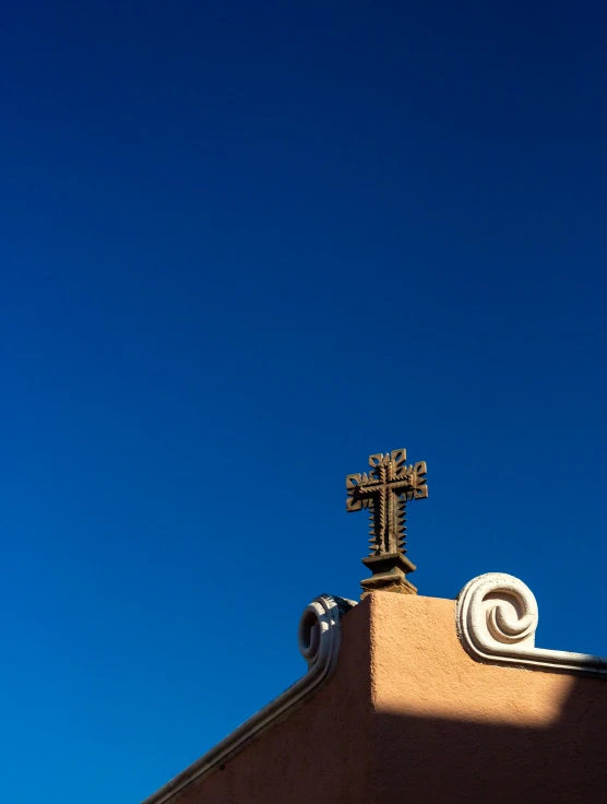 an antique crucifix stands atop the roof of a building