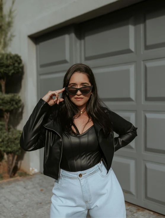 a young woman wearing sunglasses while standing next to a garage door