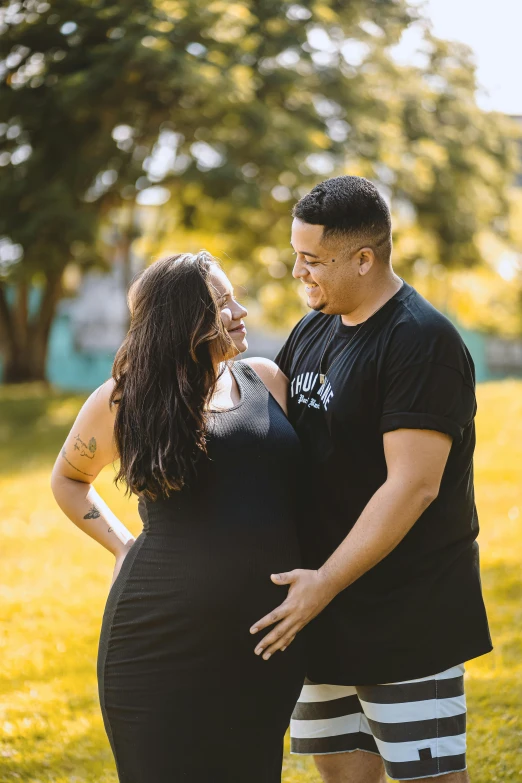 a pregnant woman in her short shorts hugging a man in a black shirt