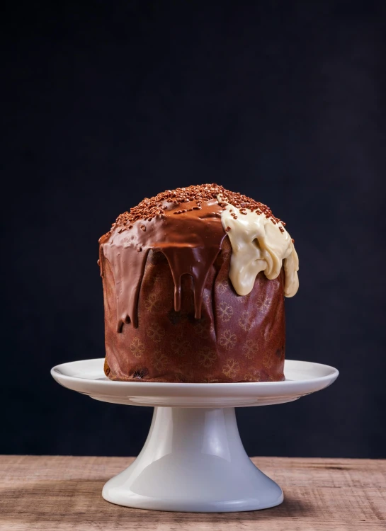 a chocolate frosted cake with nuts and frosting on a cake plate