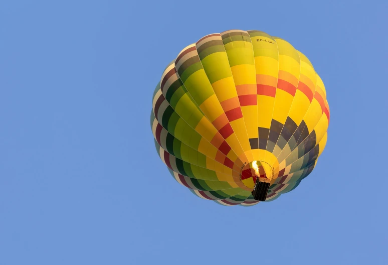 the bright yellow and red  air balloon is flying through the clear blue sky