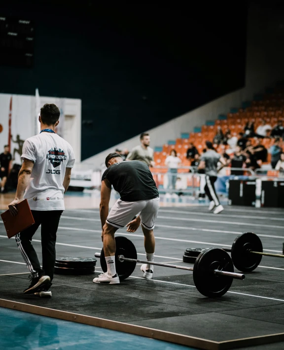 two men standing in front of their barbells on a track