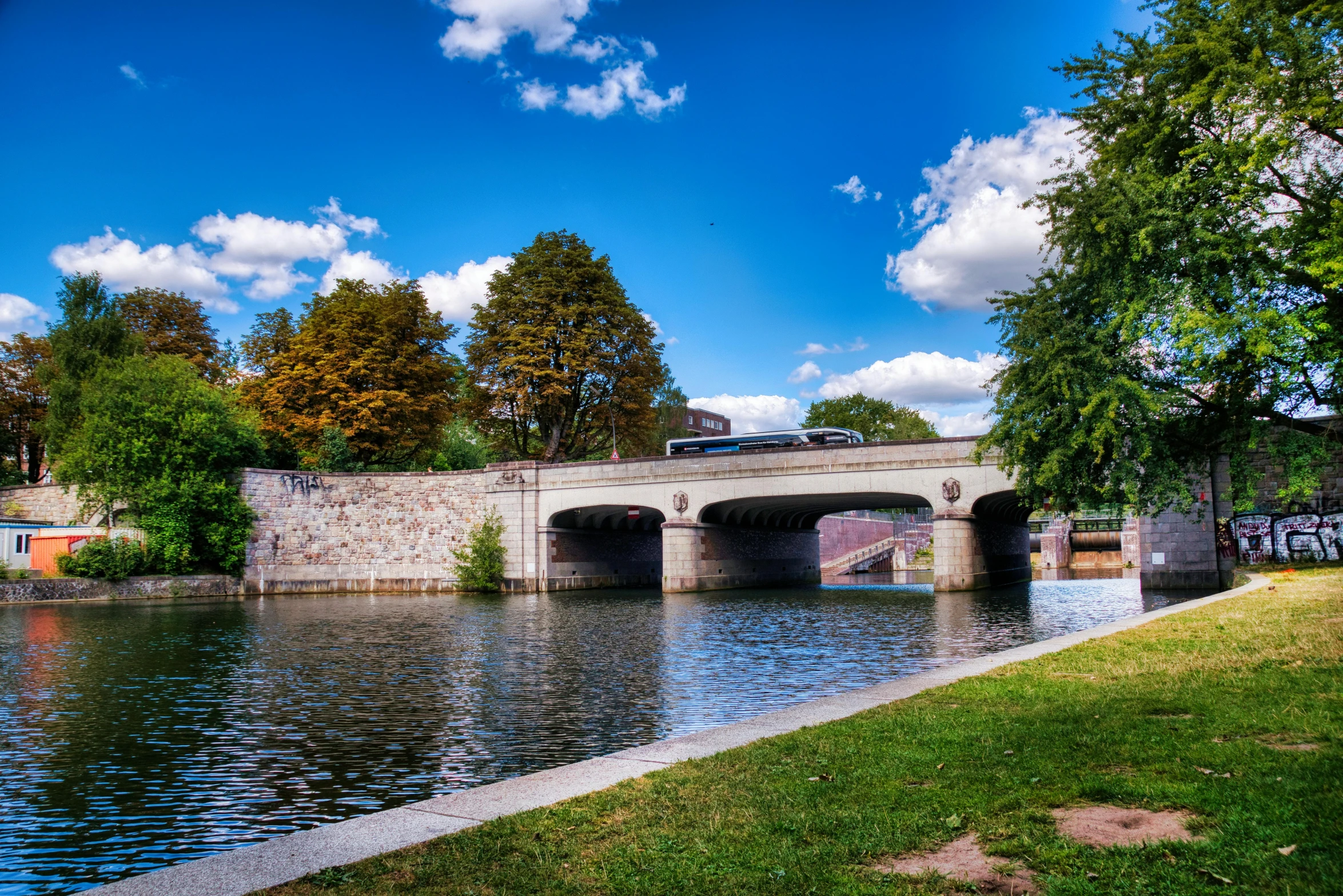 a bridge crossing over water with trees and sky