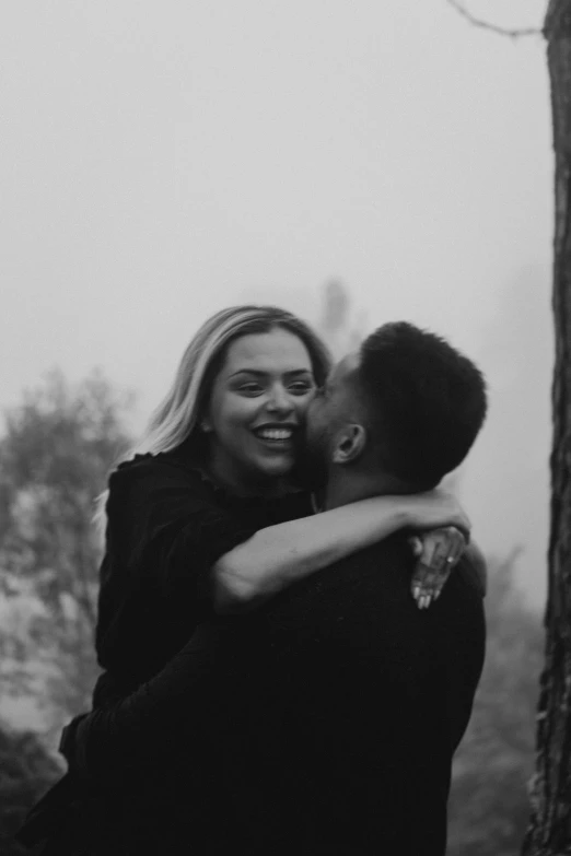 an attractive couple of people in the woods hugging