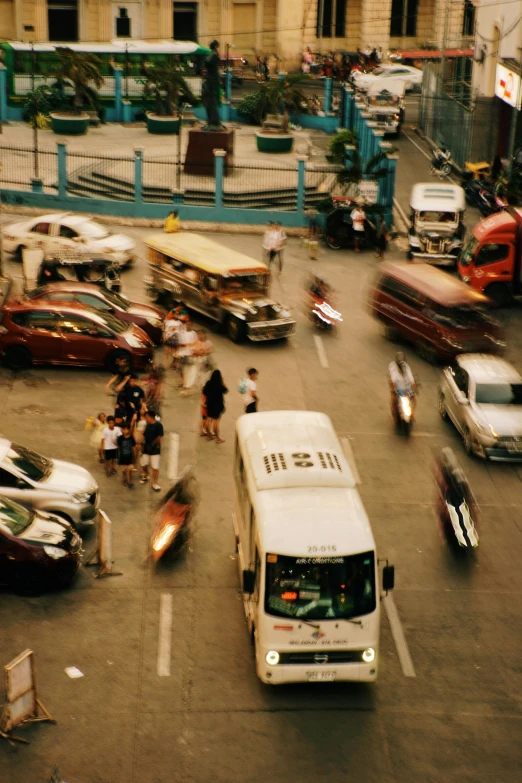 a busy city intersection shows people, cars, and buses