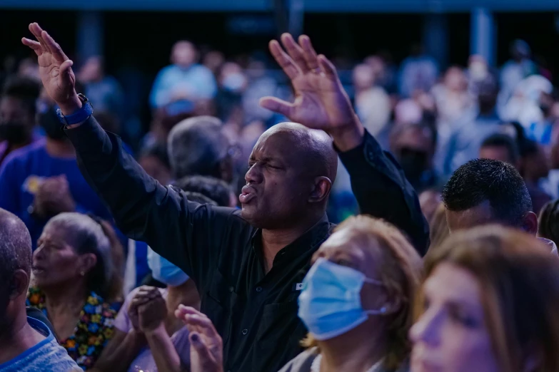 a crowd of people wearing face masks and clapping