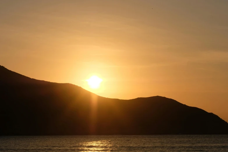 the sun shining brightly over a mountain at dusk