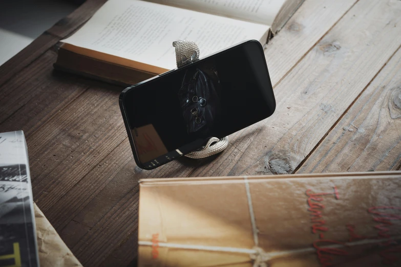 an open book on a wooden floor and a cell phone