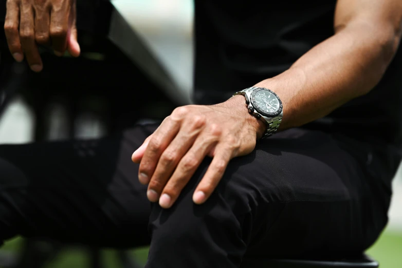 a man is sitting down and looking at his watch