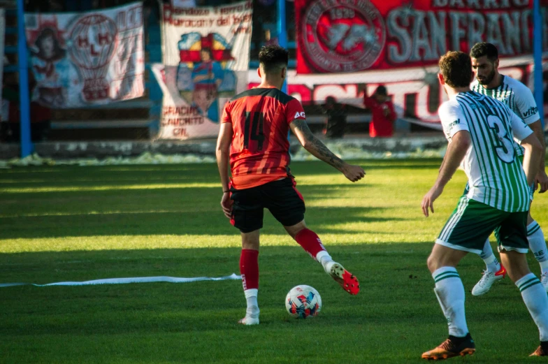 two soccer players kick the ball at the same time