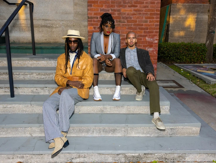 three people sitting on steps wearing hats and clothes