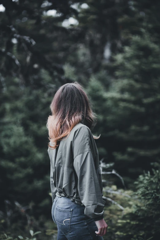 a woman standing by some trees in the woods