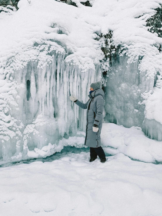 a person standing next to a frozen waterfall