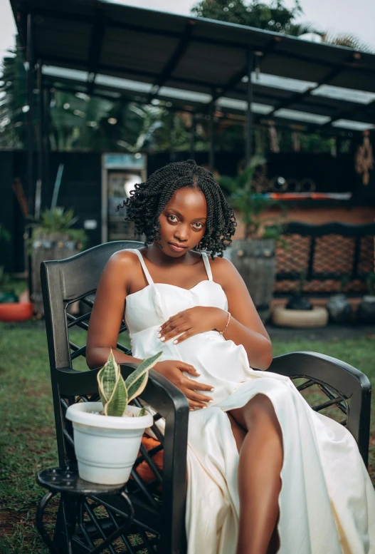 a pregnant woman sitting on a chair in a white dress