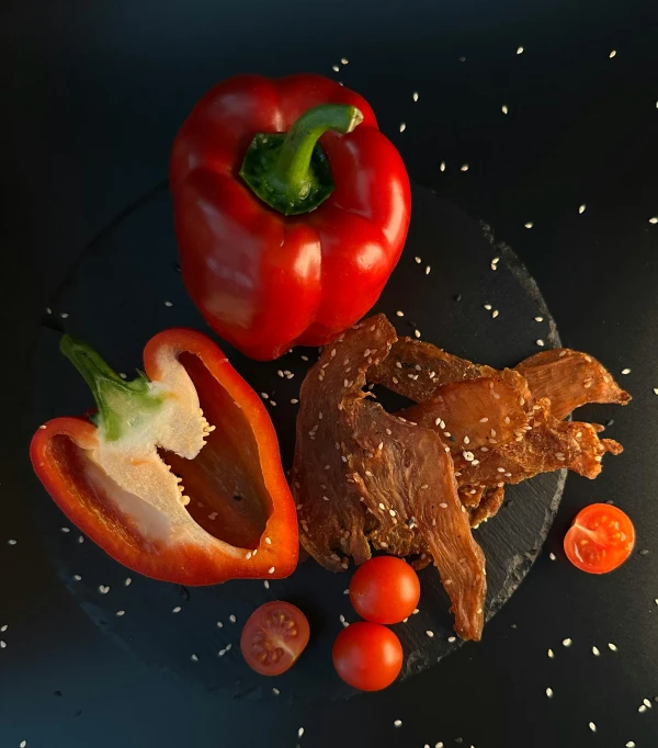 the chicken is next to the half pepper, tomatoes and peppers