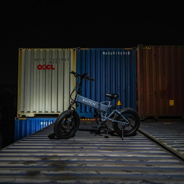 a dark bike sitting in front of containers