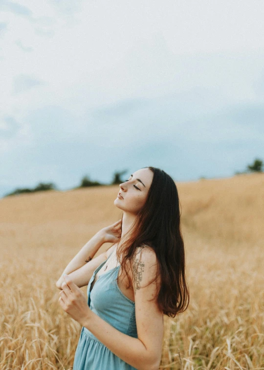 woman in blue dress standing in golden field